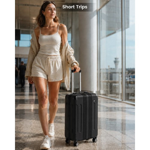 Woman pulling black 19-inch carry-on through airport terminal with extended handle and spinner wheels