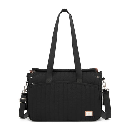 Black quilted diaper bag with vertical stitching, front zipper pocket, and embossed brand label