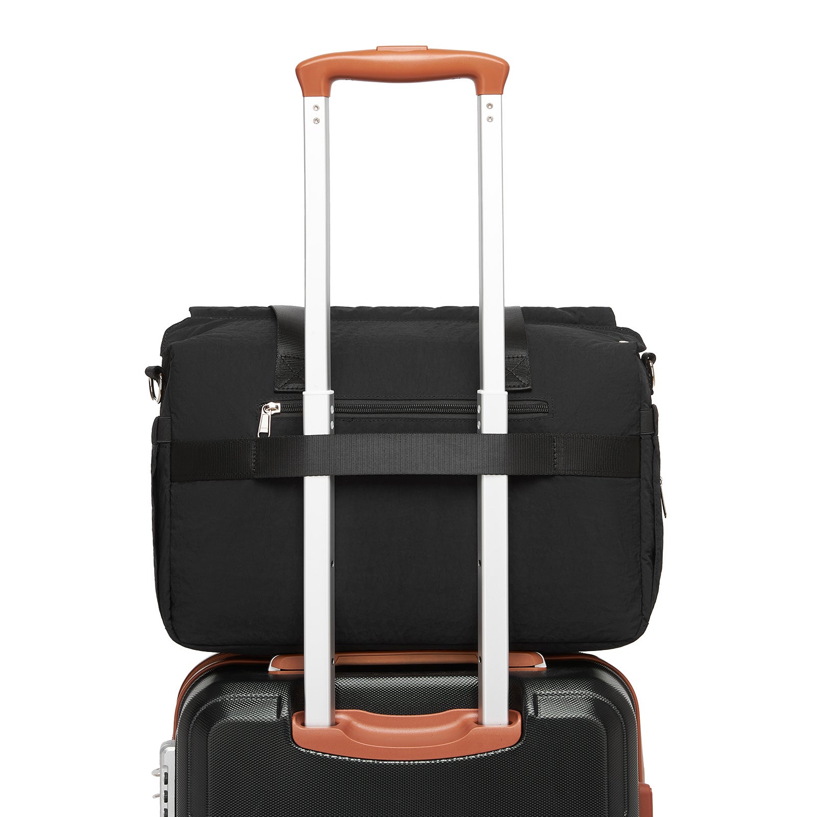 Black quilted diaper bag attached to rolling suitcase handle for travel compatibility