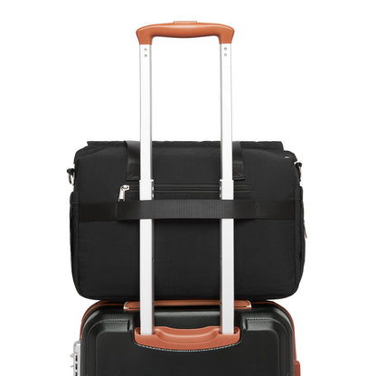 Black quilted diaper bag attached to rolling suitcase handle for travel compatibility