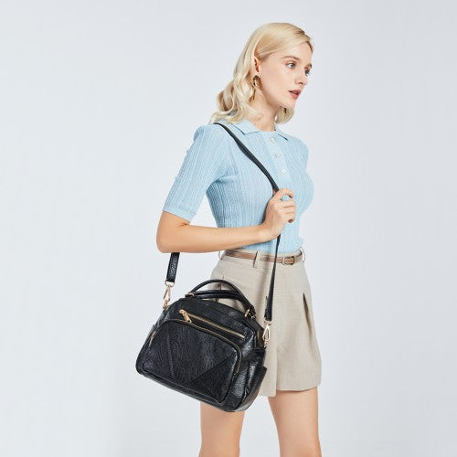 Black bowler bag worn crossbody on model demonstrating 50cm strap drop and ergonomic fit